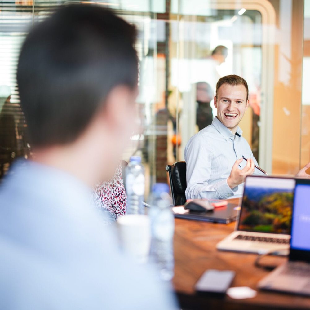 picture of a vibrant office and two colleagues around a larger table in group, spporting monday.com omplemenation
